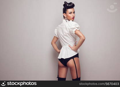 Pin up styling model posing in stocking, high shorts and white shirt. Updo.