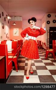 Pin up woman in red dress with white dots, vintage style. Retro cafe interior with checkerboard floor