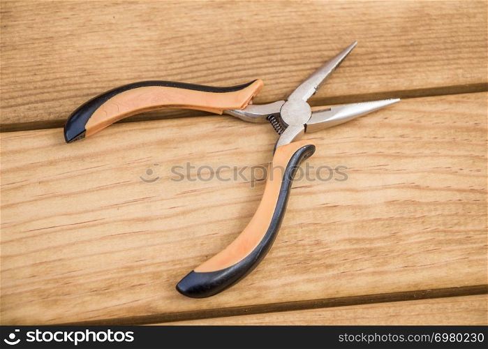 Pincer with plastic handle on a wooden background