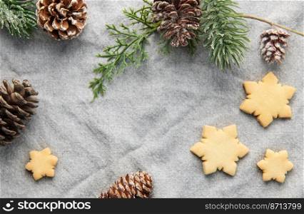 Pine branch and Christmas cookies on a textile background. The concept of preparing for the Christmas holiday. Flat lay. Copy space.  