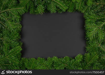 Pine Christmas tree branches on black paper background flat lay top view mock-up. Pine branches on black paper