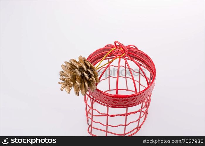 Pine cone in a red bird cage on a white background