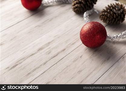 Pine cones and red christmas balls for christmas decoration on rustic white wooden background. Copy space for your text