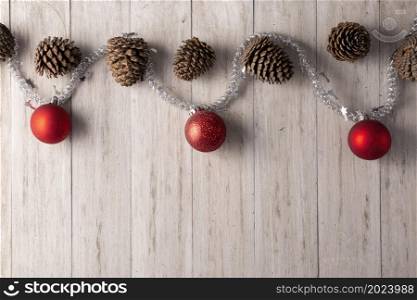 Pine cones and red christmas balls for christmas decoration on rustic white wooden background. Copy space for your text