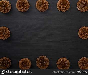 pine cones on a black wooden background, empty space in the middle