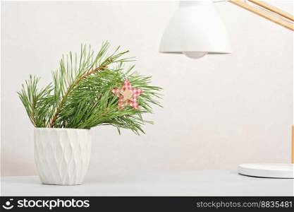 pine tree branch in white vase on table top next to desk l&. minimal christmas home decor, winter holiday office decor. copy space. pine tree branch in white vase on table top next to desk l&. minimal christmas home decor, winter holiday office decor. copy space. 