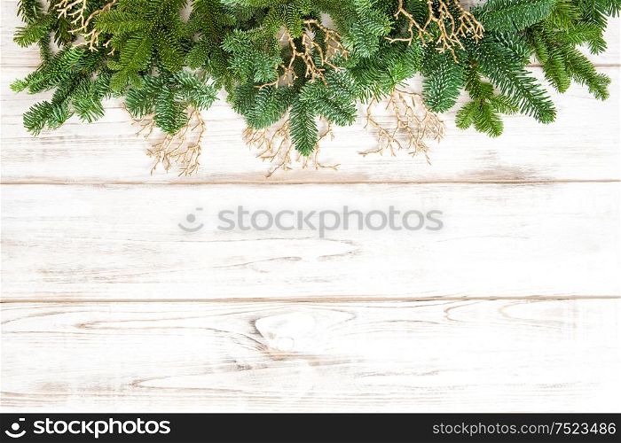 Pine tree branches with golden ornaments on wooden background