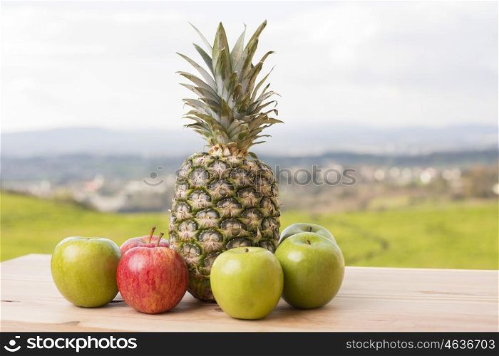 Pineapple and apple on wood table, outdoor