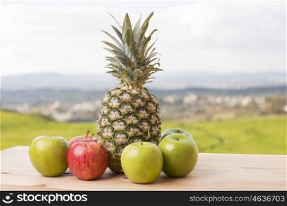 Pineapple and apple on wood table, outdoor