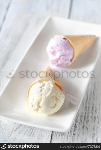 Pineapple and blackcurrant ice cream cones on the white plate