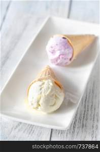 Pineapple and blackcurrant ice cream cones on the white plate