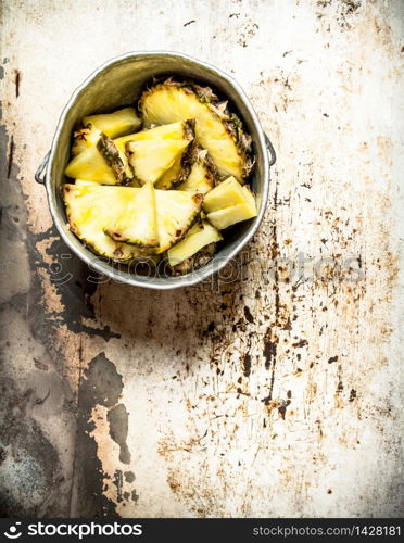 Pineapple chunks in an old pot. On rustic background.. Pineapple chunks in an old pot.