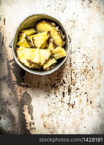 Pineapple chunks in an old pot. On rustic background.. Pineapple chunks in an old pot.