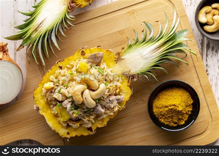 Pineapple Fried Rice with pork, egg, garlic, onion, spring onion, pepper and curry powder with cashew nut on top in wooden cutting board, top view, flat lay, Khao Pad Sapparod, famous Thai food