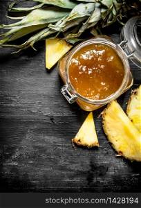 Pineapple jam in a jar. On a black wooden background.. Pineapple jam in a jar.