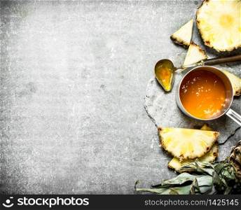 Pineapple jam in a small saucepan. On a stone background.. Pineapple jam in a small saucepan.