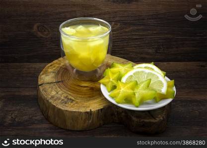 Pineapple juice and lemon with star fruit on a wooden background.