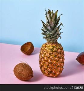 Pineapple, mango, coconut -the tropical fruits on duotone pink-blue background. Natural food.. Tropical exotic fruits pineapple, mango, coconut on a duotone pink-blue background.