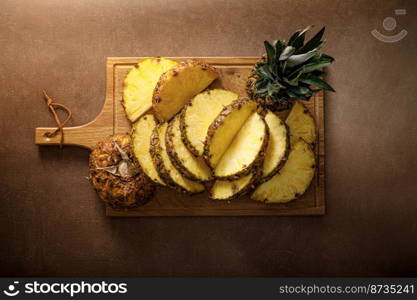 Pineapple. Sliced and whole pineapple on brown background, top vew