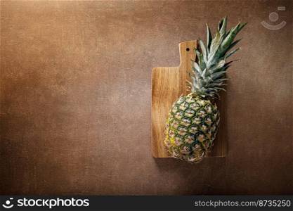 Pineapple. Whole pineapple on brown background, top view
