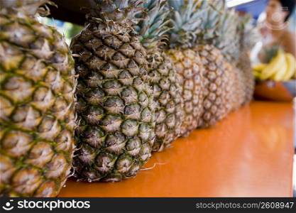 Pineapples in a row on outdoor market counter