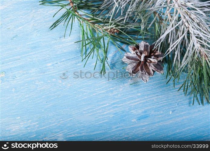 Pinecone and pine branch. In the corner of the frame. On a snow-covered wooden background. fir branches covered with snow and cones on a background of stylized snow