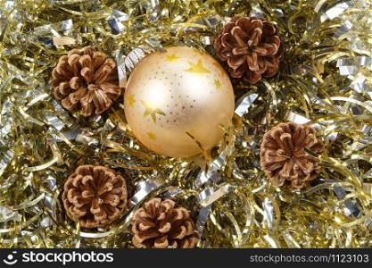 Pines cones and golden bauble on a golden tinsel as decoration for Christmas