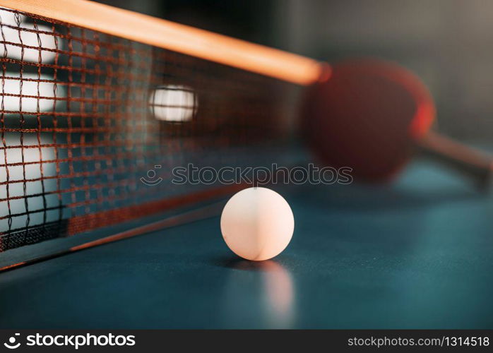 Ping pong ball on the table against net, selective focus, racket on background, game concept. Tennis sport equipment