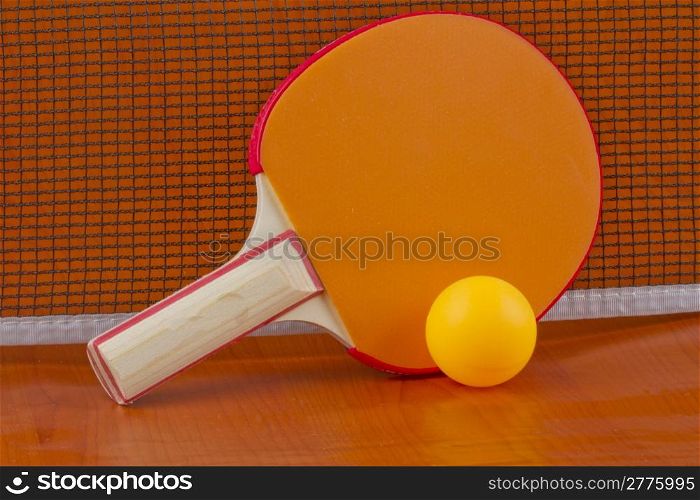 Ping pong orange racket with yellow ball near the net