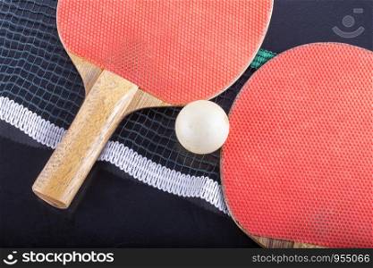 Ping pong rackets with ball and net, close up, horizontal image