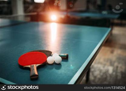 Ping pong table with rackets and balls in a sport hall, game equipment. Indoor tennis club. Ping pong table, rackets and balls in a sport hall