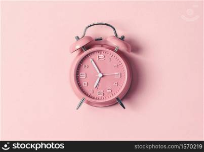 Pink alarm clock on pink background, flat lay, top view, mobochrome image
