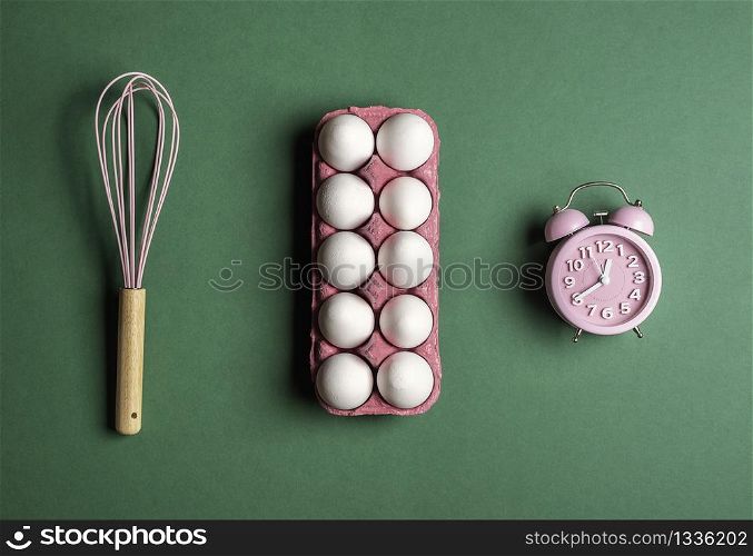 Pink alarm clock, whisk and egg cartoon on a green background. Backing time concept.