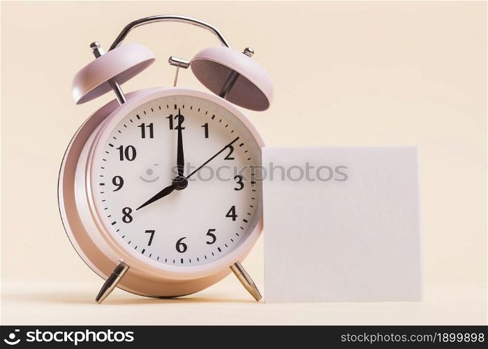 pink alarm clock with blank white adhesive note beige background. Resolution and high quality beautiful photo. pink alarm clock with blank white adhesive note beige background. High quality beautiful photo concept