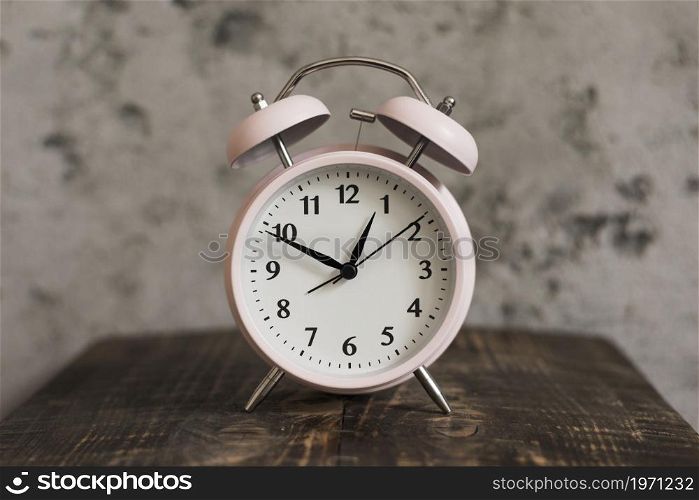 pink alarm clock wooden desk against weathered wall. High resolution photo. pink alarm clock wooden desk against weathered wall. High quality photo