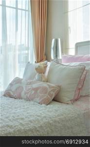 Pink and beige pillows on bed next to window