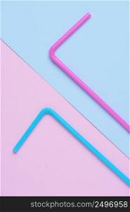 Pink and blue drinking cocktail straws on double colored trendy pastel paper background top view