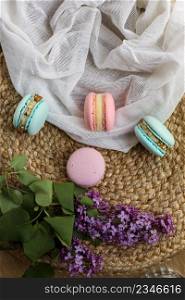 pink and mint french macaroons or macarons cookies and a lilac flowers on a cloth and straw stand background. Natural fruit and berry flavors, creamy stuffing.. pink and mint french macaroons or macarons cookies and a lilac flowers on a cloth and straw stand background. Natural fruit and berry flavors, creamy stuffing