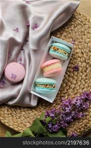 pink and mint french macaroons or macarons cookies in gift box and a lilac flowers on a cloth and straw stand background. Natural fruit and berry flavors, creamy stuffing for valentines,mother day.. pink and mint french macaroons or macarons cookies in gift box and a lilac flowers on a cloth and straw stand background. Natural fruit and berry flavors, creamy stuffing for valentines,mother day