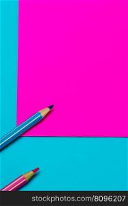 pink and turquoise colored pencils on a bright pink and turquoise background with copy space as a background
