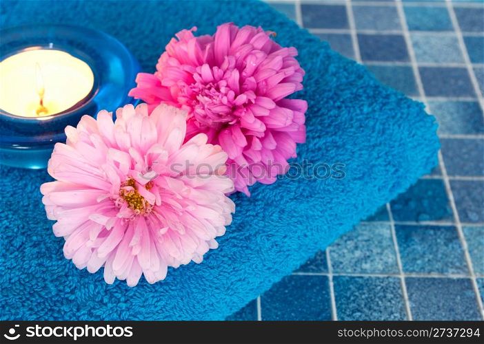 Pink and Violet Dahlia Flowers, towel and Candle on Blue Bathroom Tiles