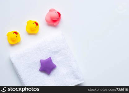 Pink and yellow duck toys and white towel, white background. Kids bath concept.