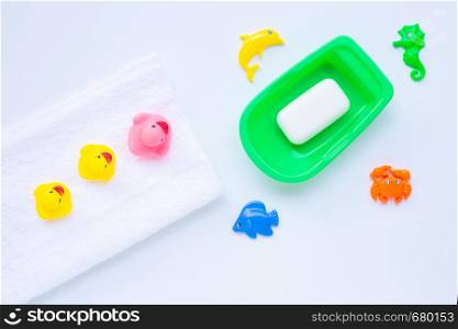 Pink and yellow duck toys on white towel with soap and sea animals on white background. Kids bath concept.