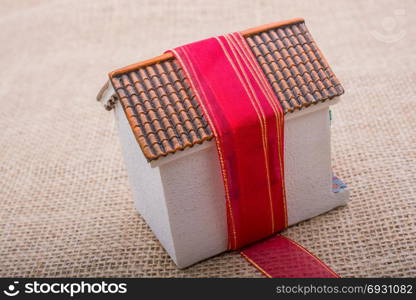 Pink band wrapped around a model house on a brown background