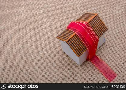 Pink band wrapped around a model house on a brown background