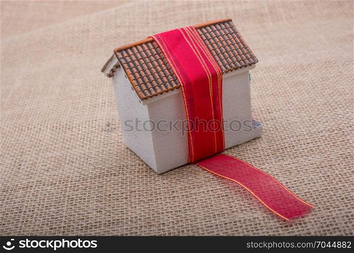 Pink band wrapped around a model house on a brown background
