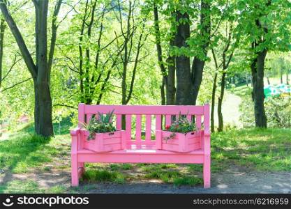 Pink bench with flowers in the green spring park