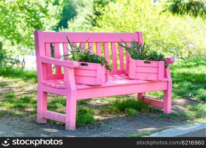 Pink bench with flowers in the green spring park