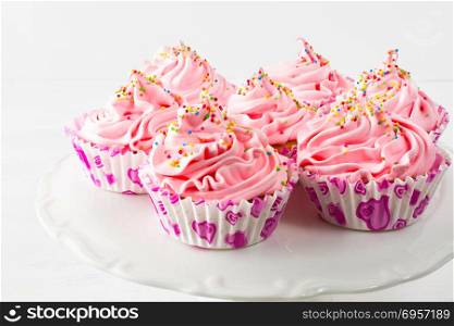 Pink birthday cupcakes on cake stand. Pink birthday cupcakes on cake stand. Birthday cupcake with pink whipped cream. Homemade cupcakes served for party.