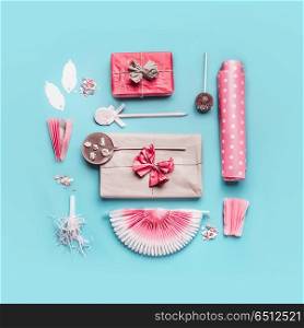 Pink birthday holidays party accessories : gift boxes with ribbon, wrapping paper, chocolate lolly pops , party fan and decor on pastel blue background, top view, flat lay